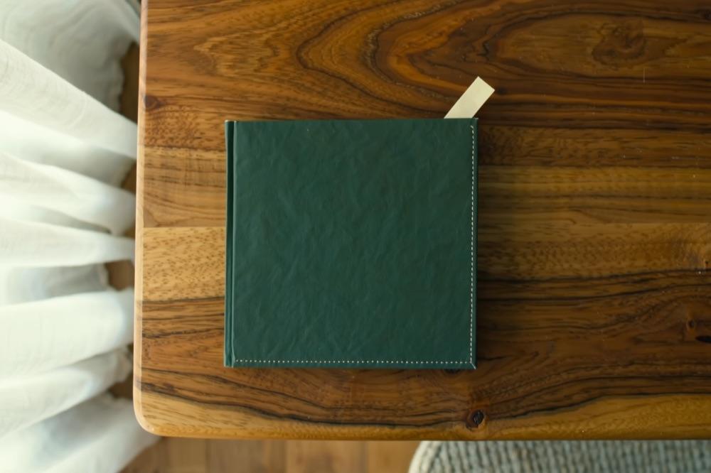 A small booklet with a plain deep green cover and a bookmark tab